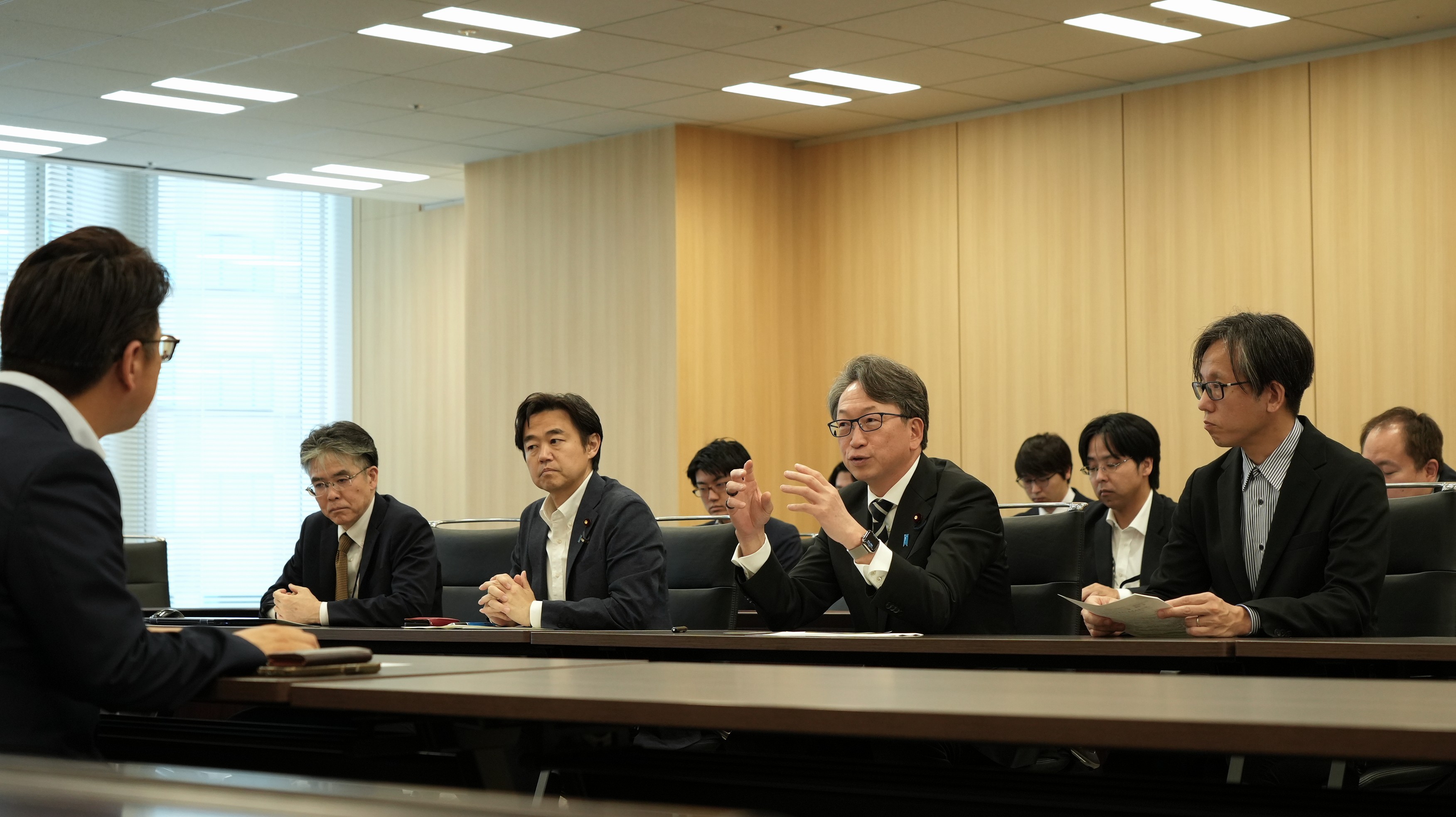 A picture of us sitting at desks facing each other and having a discussion, with Mr. Taira, Minister for Digital Transformation, speaking in the center
