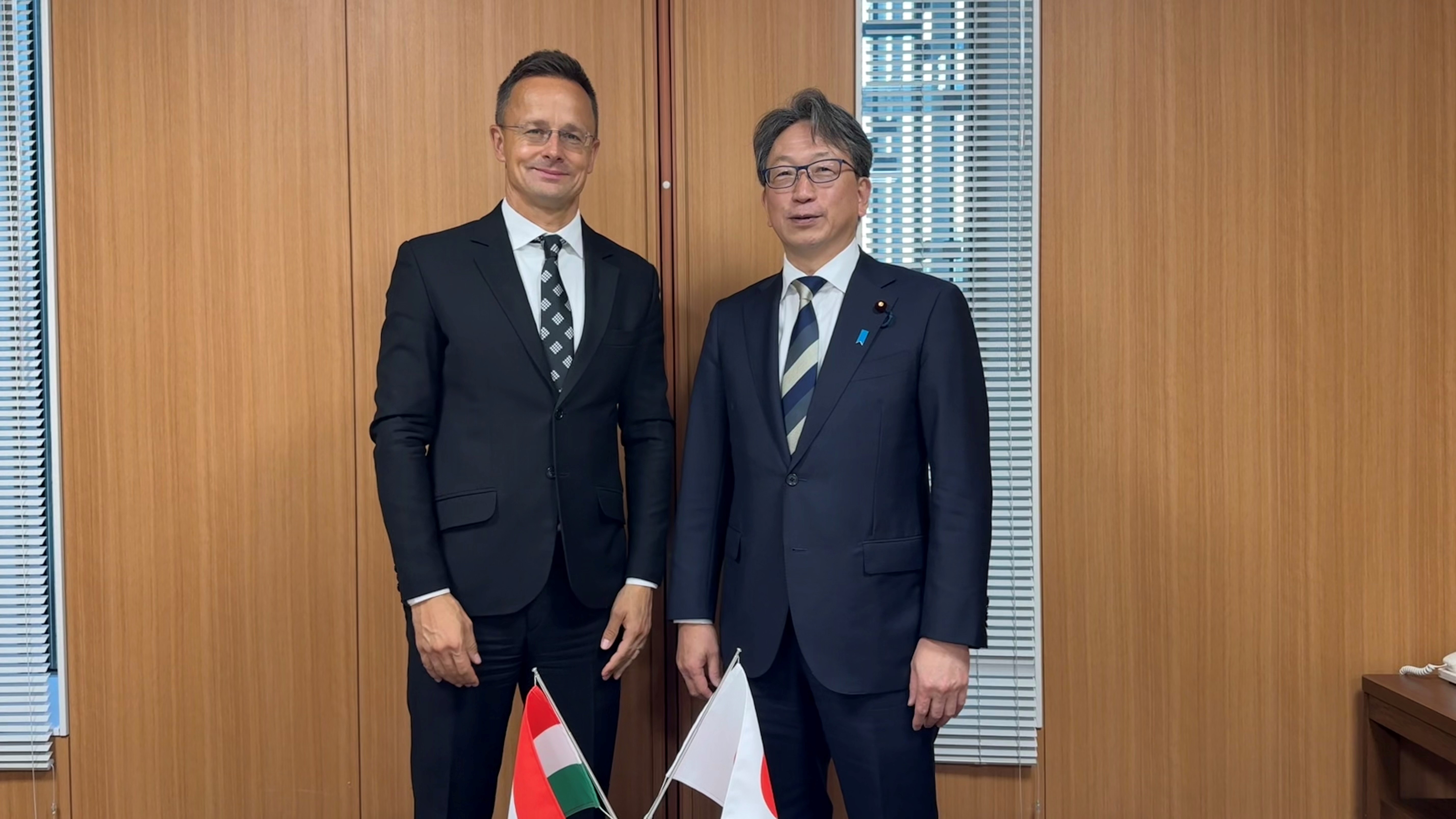 Mr. Péter Szijjártó, Minister of Foreign Affairs and Trade of Hungary, stands on the left, with Minister Taira on the right. The flags of Hungary and Japan are displayed at the bottom center of the image.