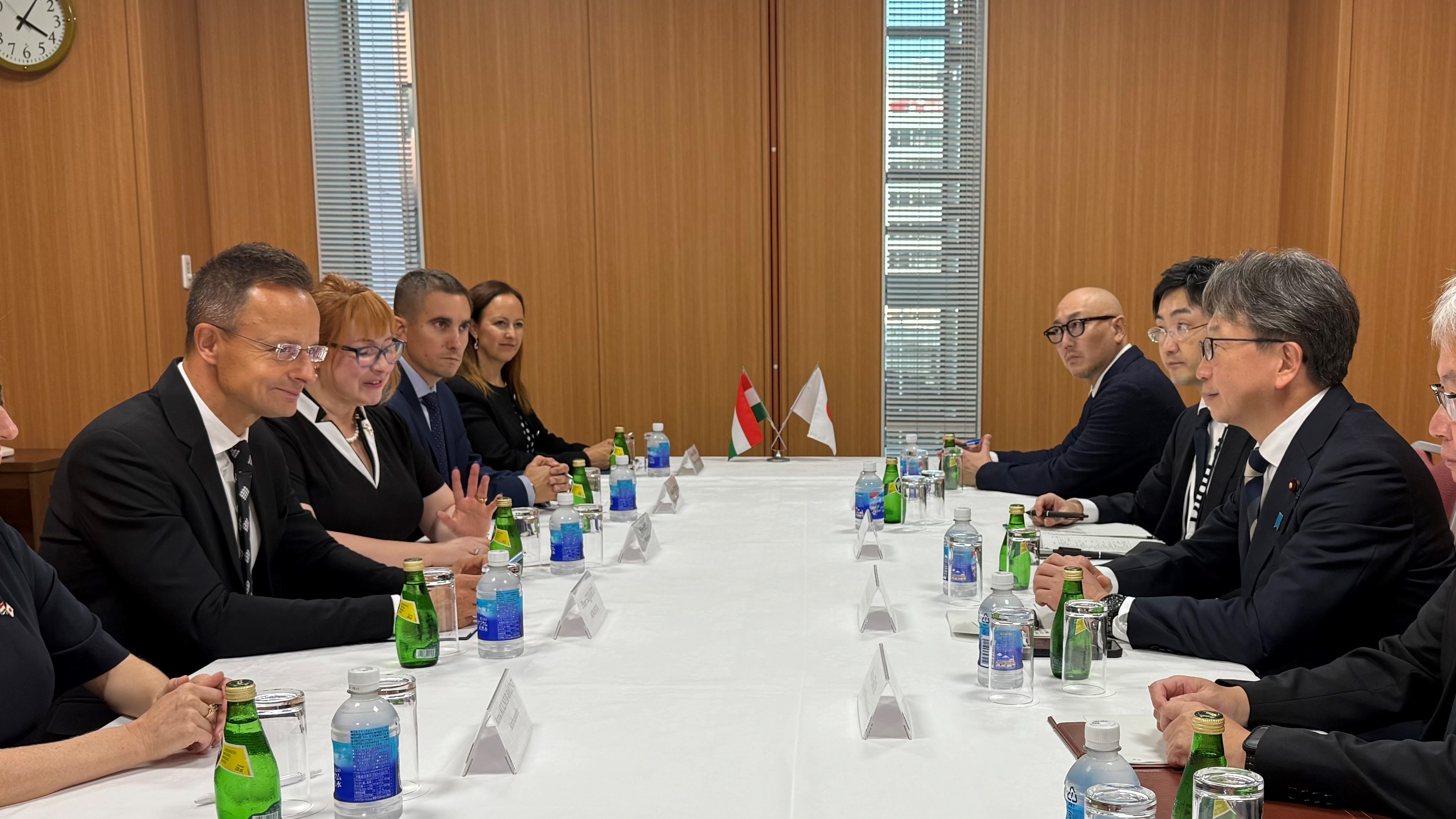 A photo showing Mr. Péter Szijjártó, Minister of Foreign Affairs and Trade of Hungary, seated on the left side of a table, with Minister Taira on the right. In the center at the far end of the table, the flags of Hungary and Japan are displayed.