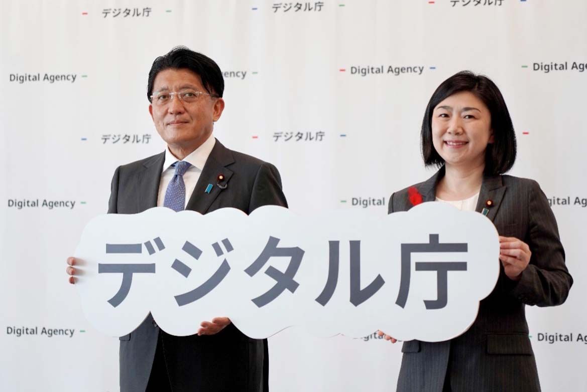 Two shots of former Minister for Digital Transformation HIRAI Takuya and new Minister for Digital Transformation MAKISHIMA Karen, both holding the Digital Agency logo.