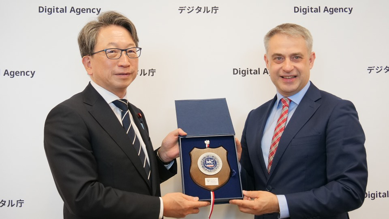 A photo of Minister Taira receiving a commemorative plaque from Poland’s Deputy Prime Minister and Minister of Digital Affairs Gafkowski, with a Digital Agency panel in the background.