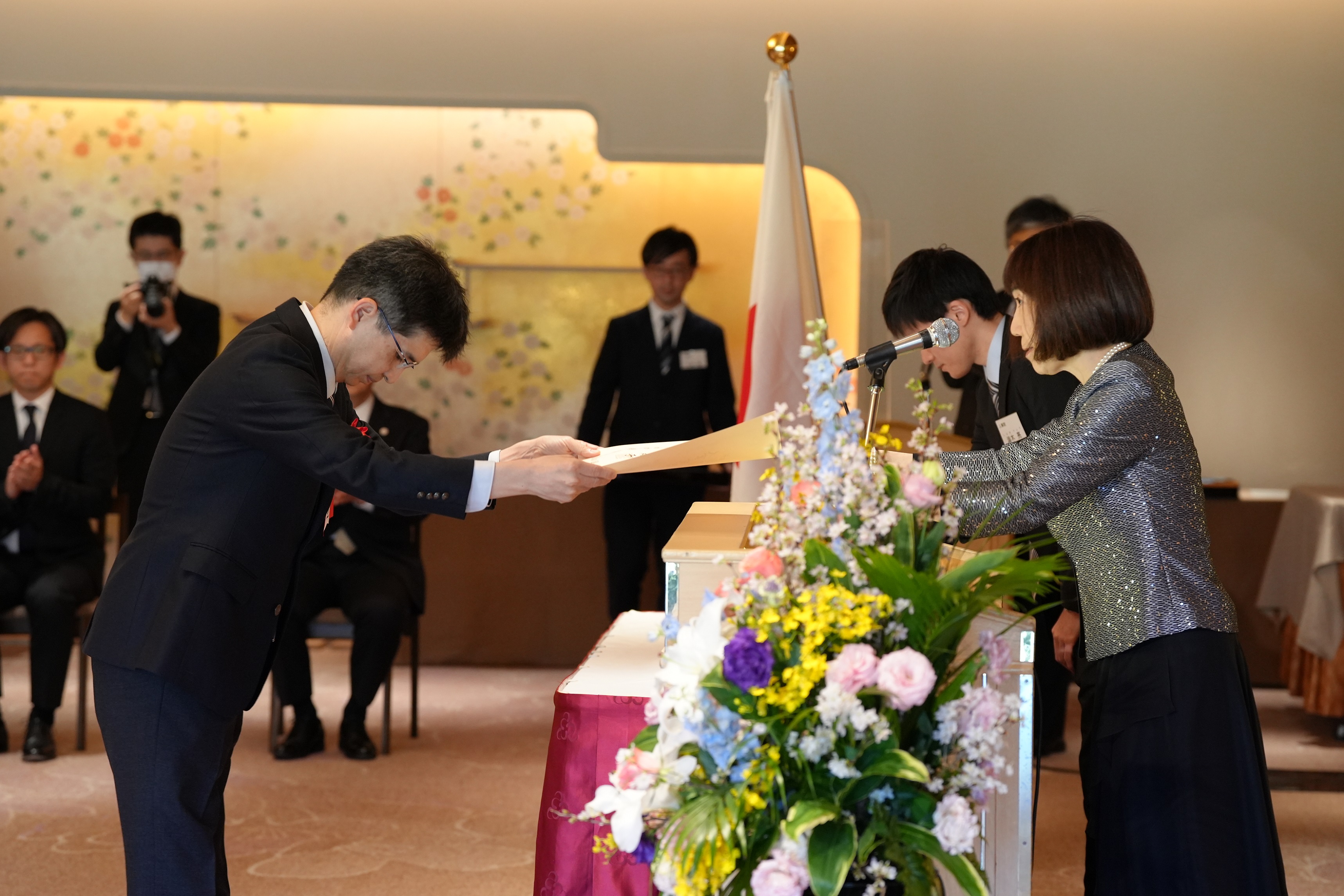 A scene where the award ceremony is being held at the Meiji Memorial Hall. The Digital Administrator receives the award certificate from President Yuko Kawamoto (National Personnel Authority).