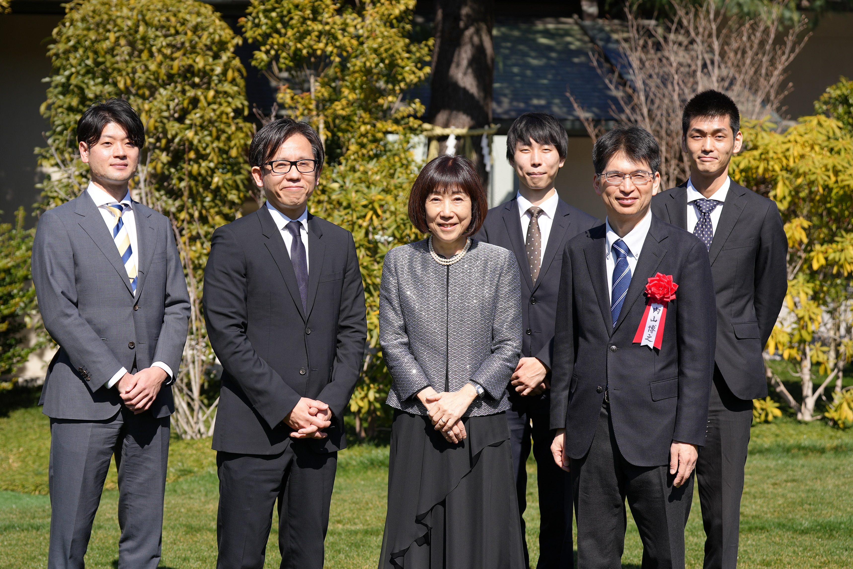 A group photo shows President Yuko Kawamoto (National Personnel Authority), Chief Officer of the Digital Agency Takashi Asanuma, Digital Commissioner and VRS team members standing in a line outside, with trees in the background.
