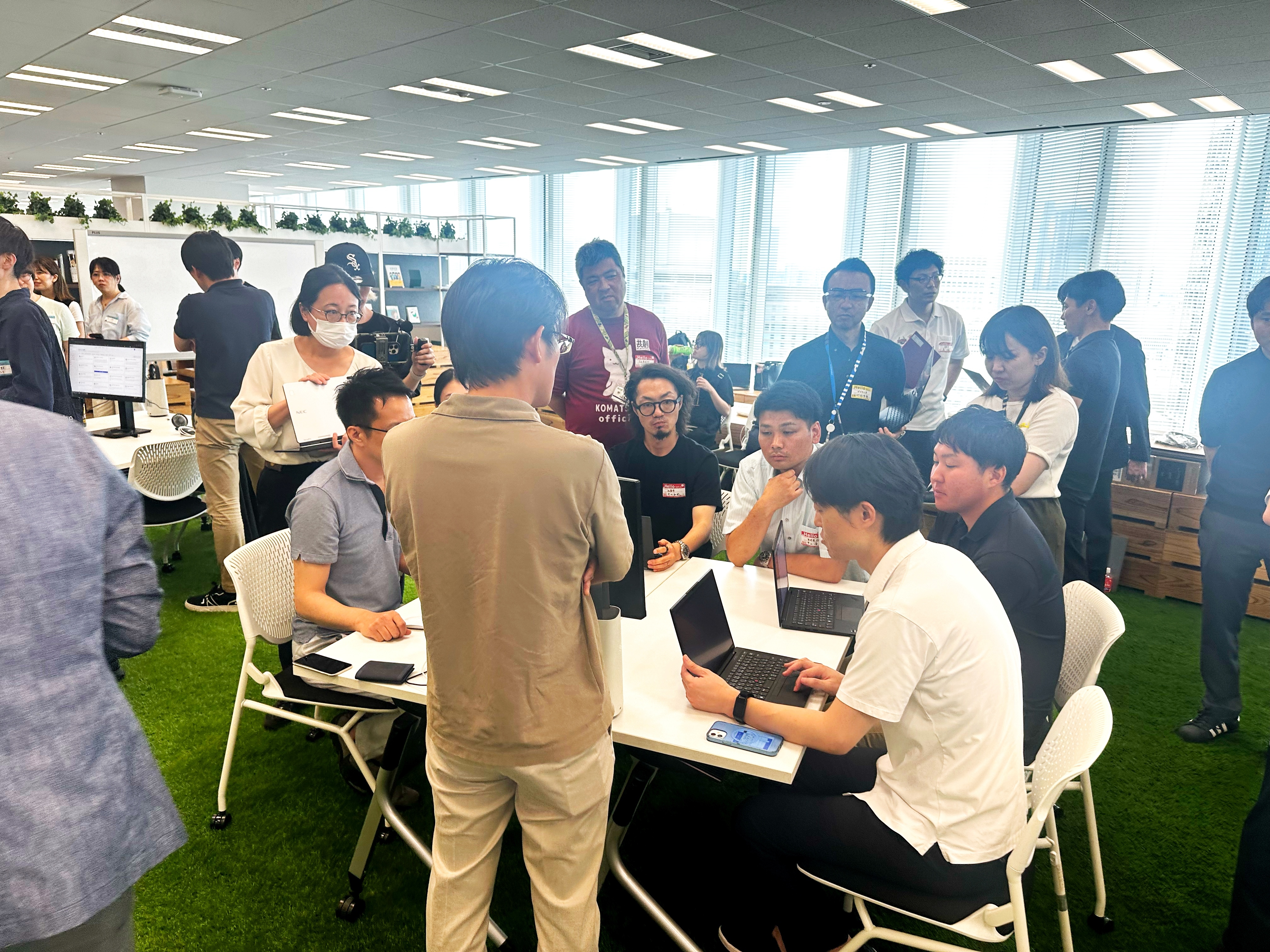 For each desk, six participants and four persons in charge of the Secretariat are listening to one presenter. Two or three other groups are gathered behind and to the right and left of each desk.