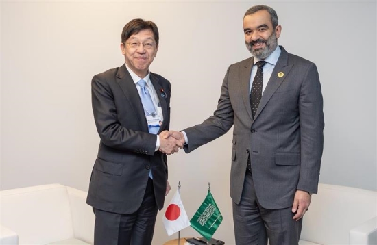 松本デジタル大臣とサウジアラビア　アル＝スワーハ大臣の2名がテーブルを挟んで握手している。テーブルには日本国旗とサウジアラビア国旗が置かれている。
