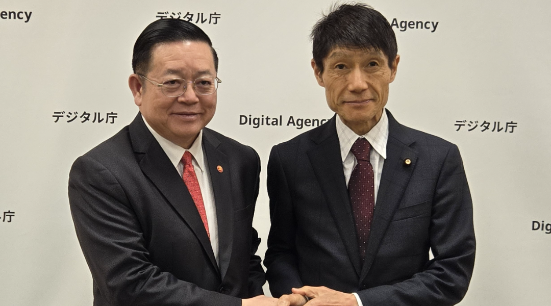 ASEAN Secretary General Cao (left) and Minister for Digital Transformation Furukawa (right) shake hands in front of the logo panel in Digital Agency.